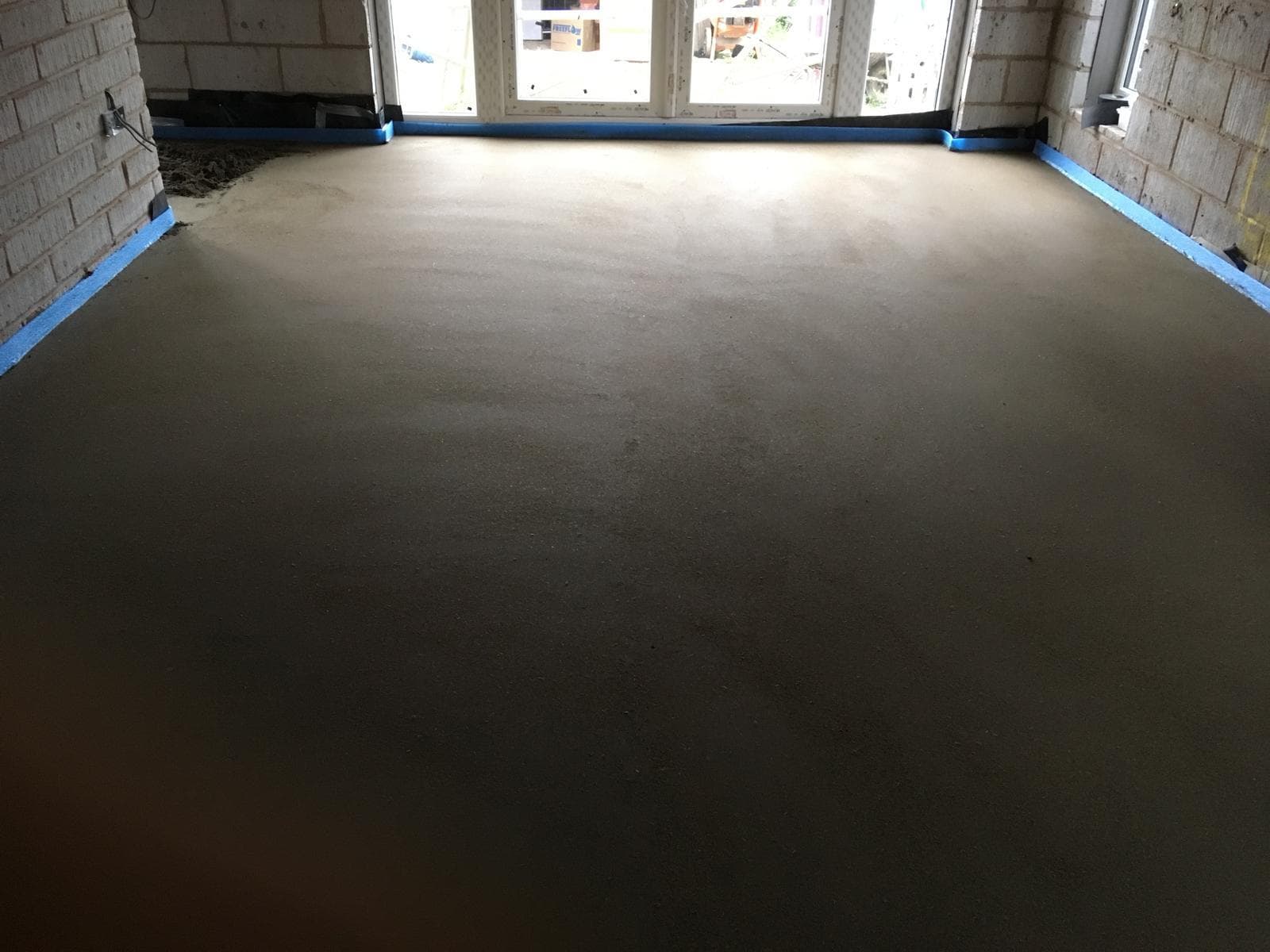 Freshly laid floor screed running through a ground-floor room.