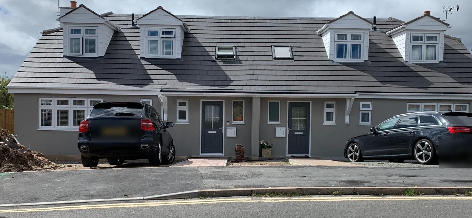 Completed pair of chalet-style conversions with white dormer windows and new tiled roofs.