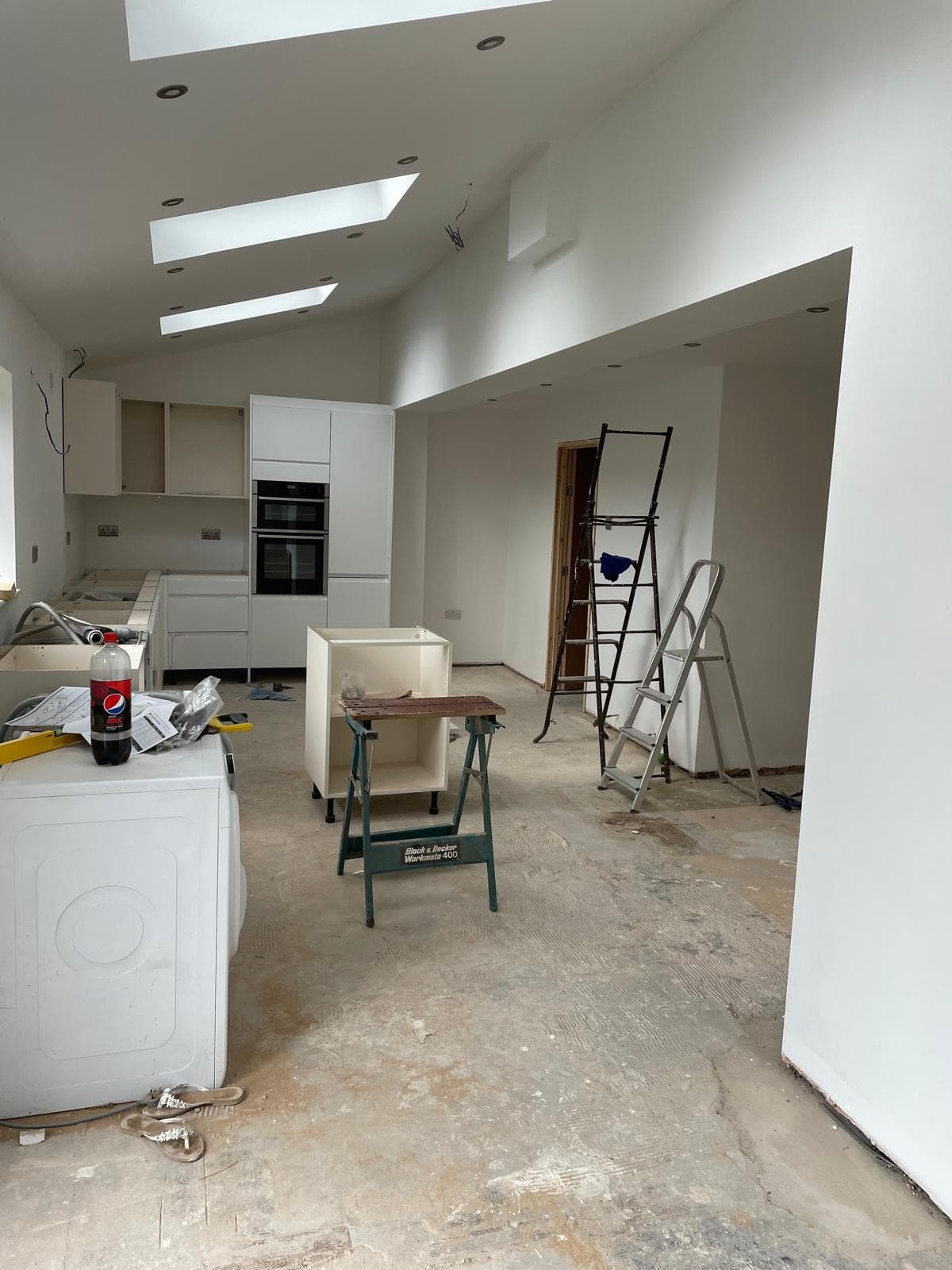 Newly plastered open-plan extension with a vaulted ceiling and recessed rooflights.