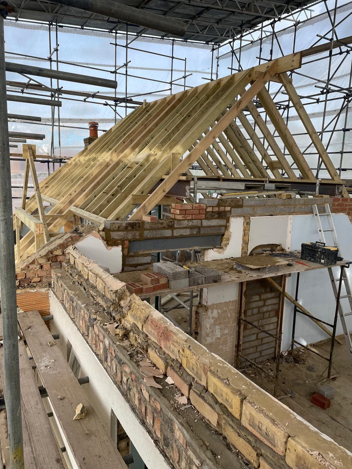 New roof timbers being framed above an existing structure.