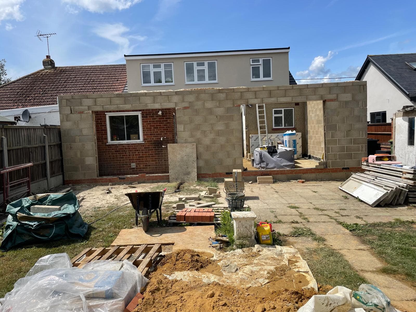 Blockwork extension shell seen from the garden, groundworks in progress.