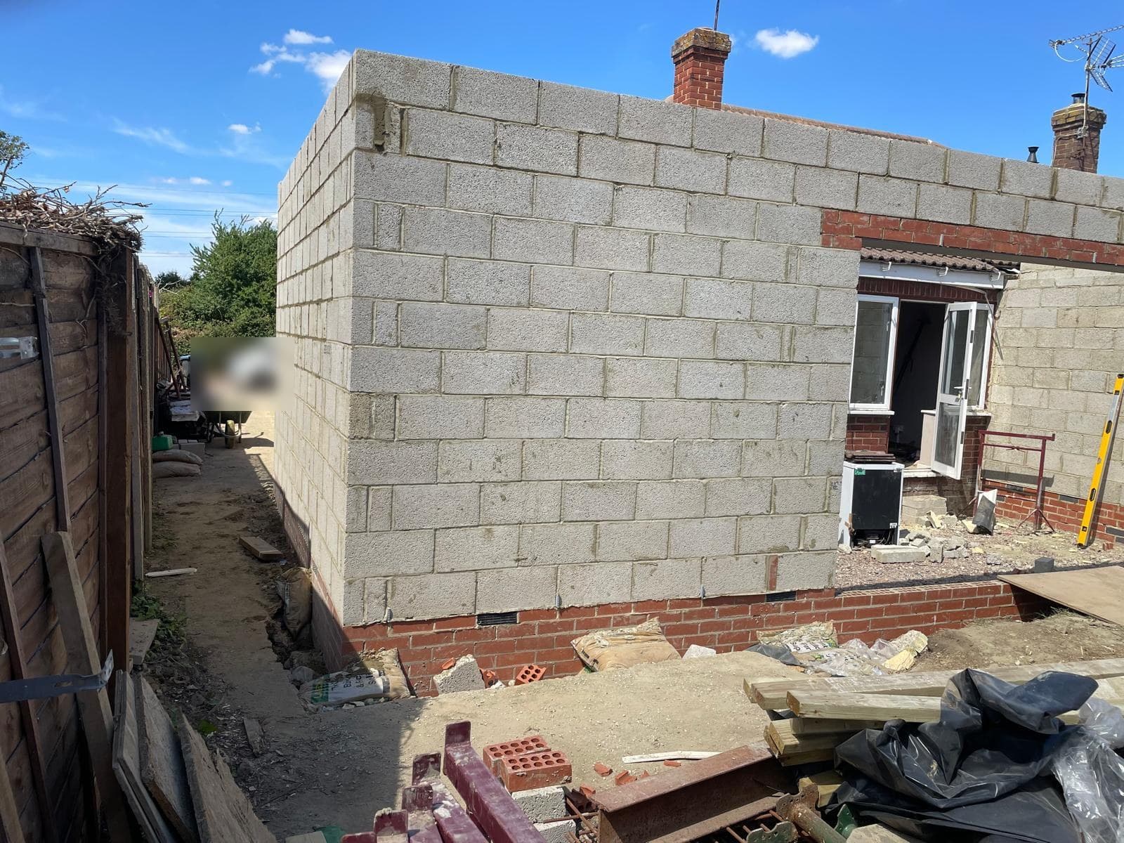 New blockwork side wall running along a narrow access path.