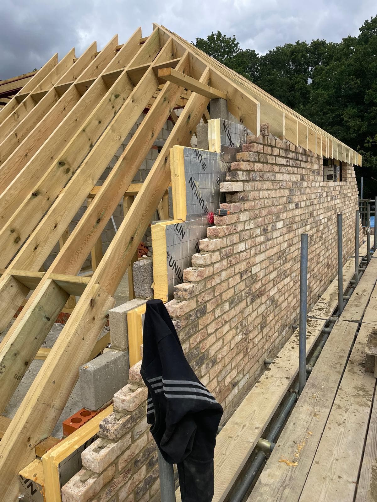 New roof timbers above a reclaimed brick wall, seen from the scaffold.