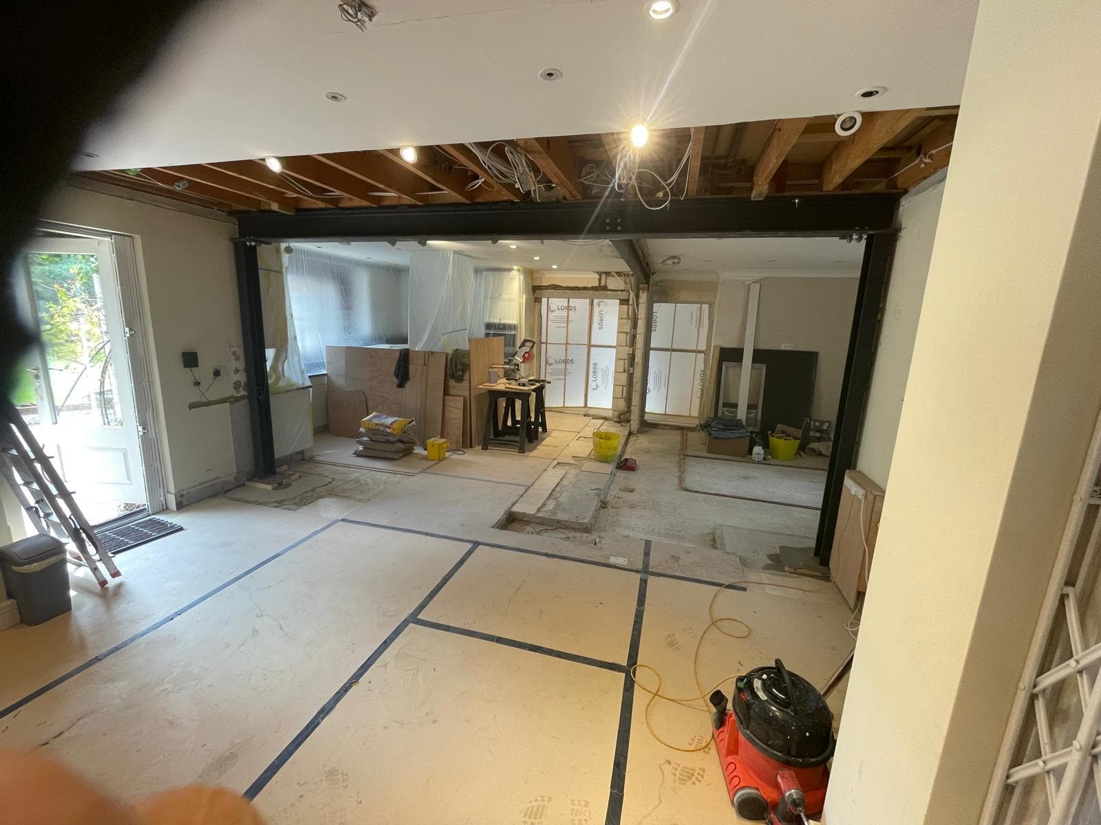 Open-plan interior after a structural knock-through, steels exposed.