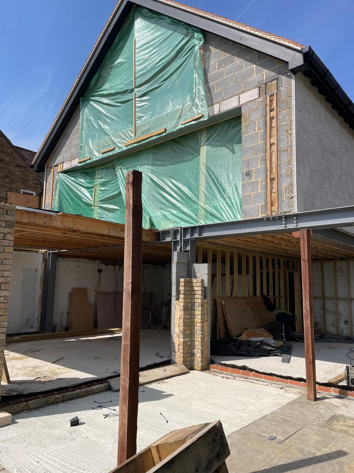 Gable end wrapped for weather protection above a new steel-framed opening.